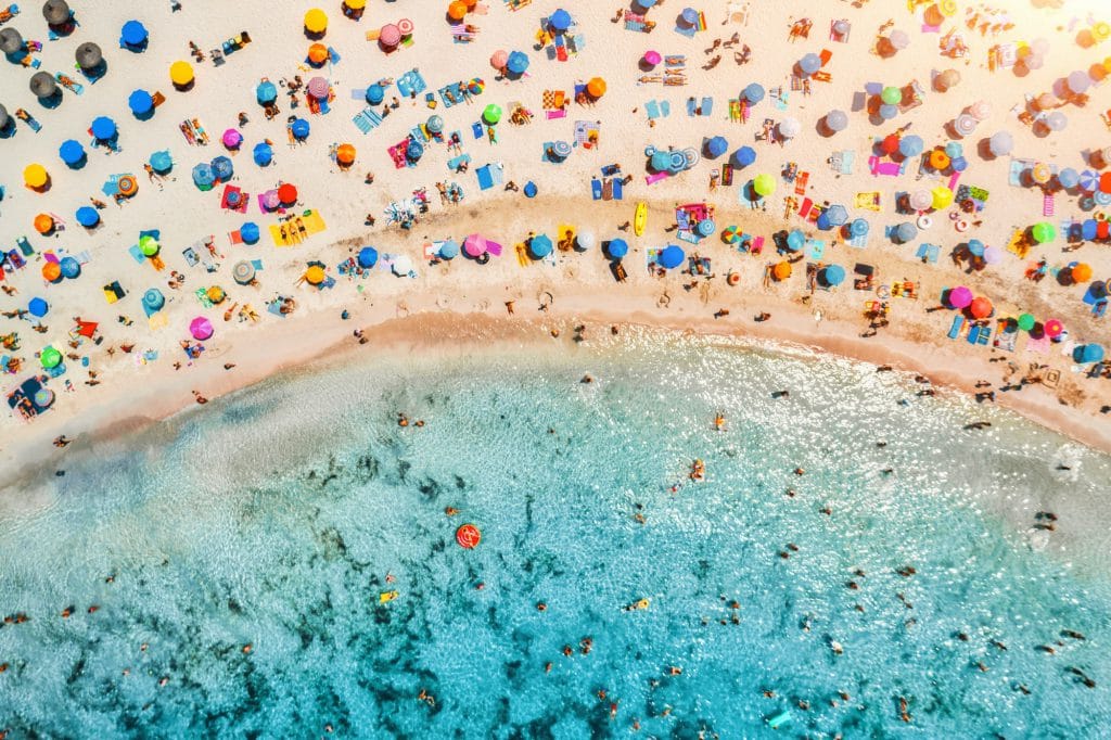 Aerial view of sandy beach with umbrellas and sea at sunset
